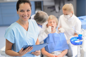 Smiling dental assistant with a patient in the background